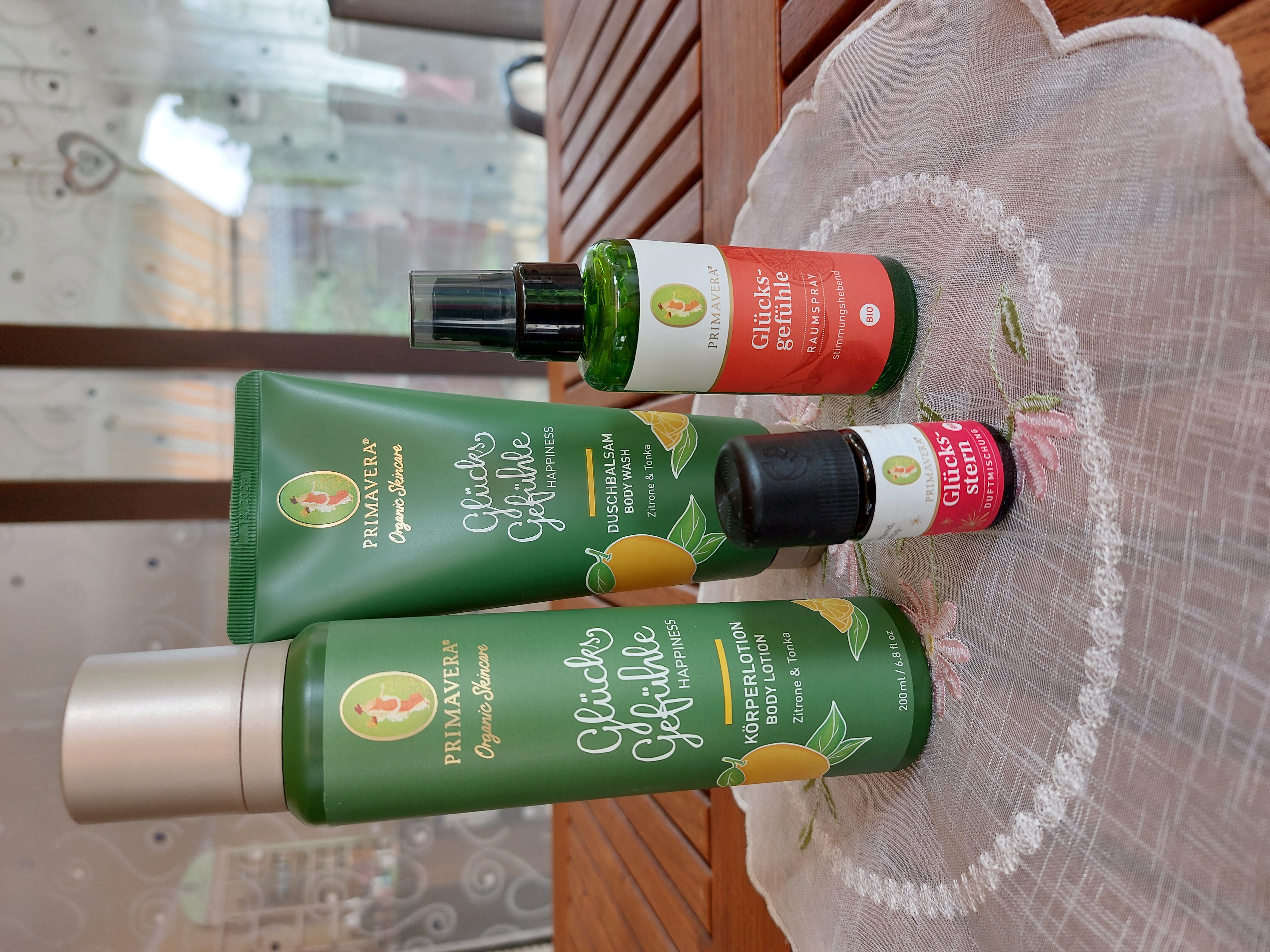 4 kleine und große Flaschen bzw. Tuben stehen auf einem Deckchen. Alle sind von Primavera.